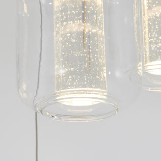 Close-up of the Artika Champagne Globe 4-light LED pendant, showcasing its modern clear glass shade and illuminated cylindrical diffuser with sparkling bubble details.