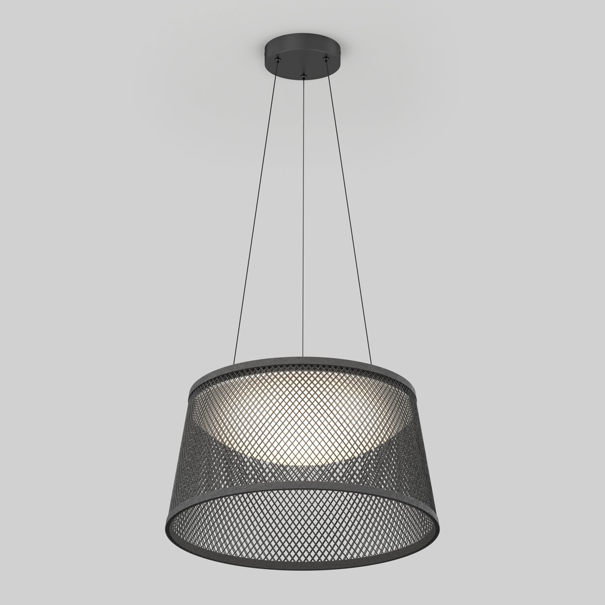 A modern pendant light with a black circular mesh shade, suspended from the ceiling by three thin wires, emits a soft, diffused glow against a plain light gray background.