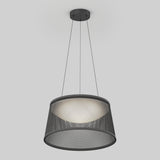 A modern pendant light with a black circular mesh shade, suspended from the ceiling by three thin wires, emits a soft, diffused glow against a plain light gray background.