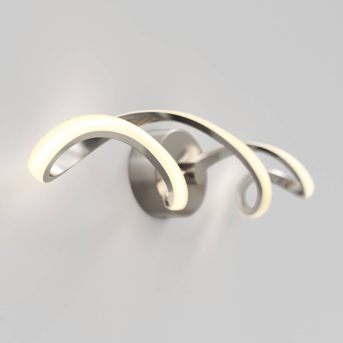 A modern wall-mounted light fixture with three curved, metallic arms, each featuring integrated LED lighting, emitting a soft, warm glow against a plain white wall.