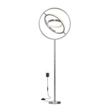 A modern floor lamp with a circular LED light ring suspended within a larger metal ring, mounted on a slim pole with a round base, and plugged into a wall outlet.