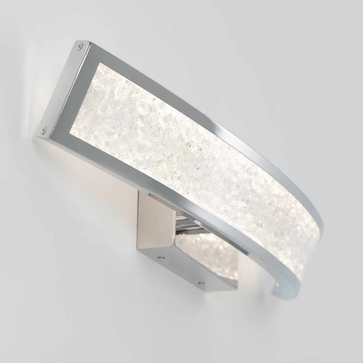 The Artika Glitter 27-in Integrated LED Vanity Light Bar for Bathroom features a modern curved rectangular design with a chrome frame and frosted, textured glass, elegantly illuminating a plain white wall.
