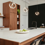 Modern kitchen with a large white marble island, black faucet, and a bowl of green apples. Wooden cabinets, unique pendant lights, and black textured wall in the background create a contemporary look.
