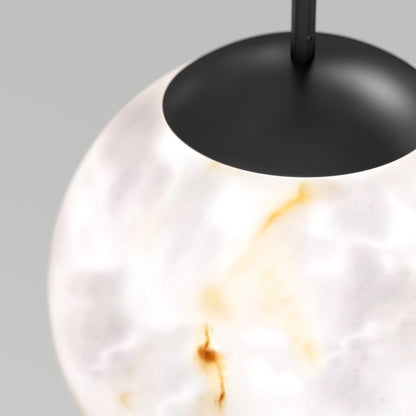 A close-up of the Artika Selena LED contemporary pendant light shows its round, cloudy white glass shade with brown and gold marbling, topped by a matte black fixture.