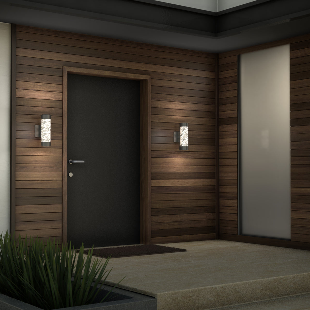 A modern front entrance with a dark door, wood-paneled walls, two wall-mounted lights, a doormat, and a frosted glass window, with a concrete step and decorative plants in the foreground.