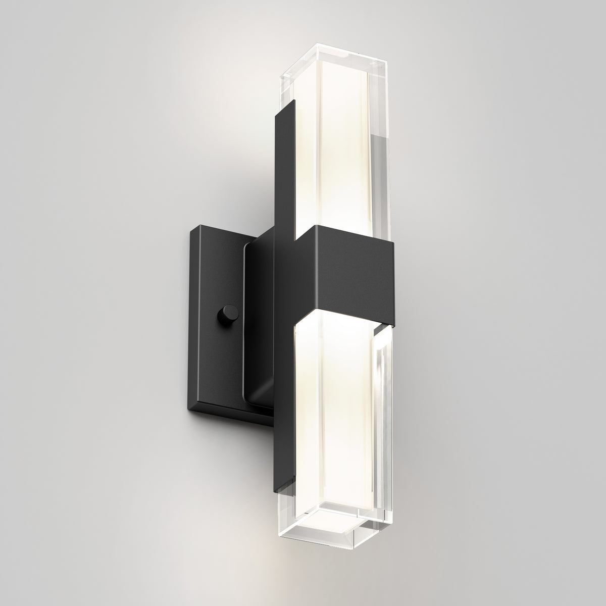 The Artika Gemini indoor-outdoor LED wall light features a black rectangular base and a vertical fixture with frosted and clear sections, mounted on a white wall to emit a soft, inviting glow.