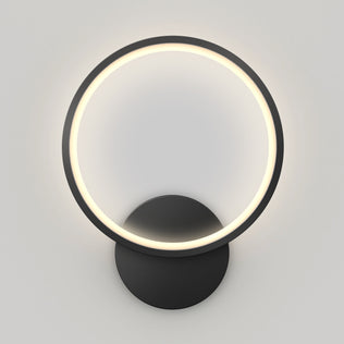 The Artika Solis modern LED indoor-outdoor wall light 5 CCT features a circular LED ring on a round black base, delivering a soft, even glow against a light gray wall.