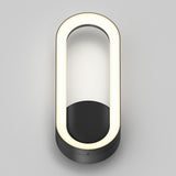 A modern wall-mounted lamp with an oval-shaped LED light ring and a black base, photographed against a light gray background. The design is minimalistic and contemporary.