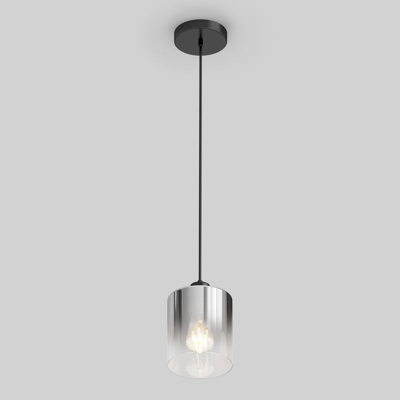 The Artika Haze pendant light glass features a modern design with a black ceiling mount and cable, a cylindrical clear glass shade, and an exposed bulb, all set against a plain light gray background.
