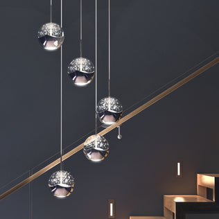 The Artika Oracle modern 5-light LED pendant features reflective, spherical shades that emit a soft, star-like glow above a staircase with dark steps and walls illuminated by small rectangular lights.