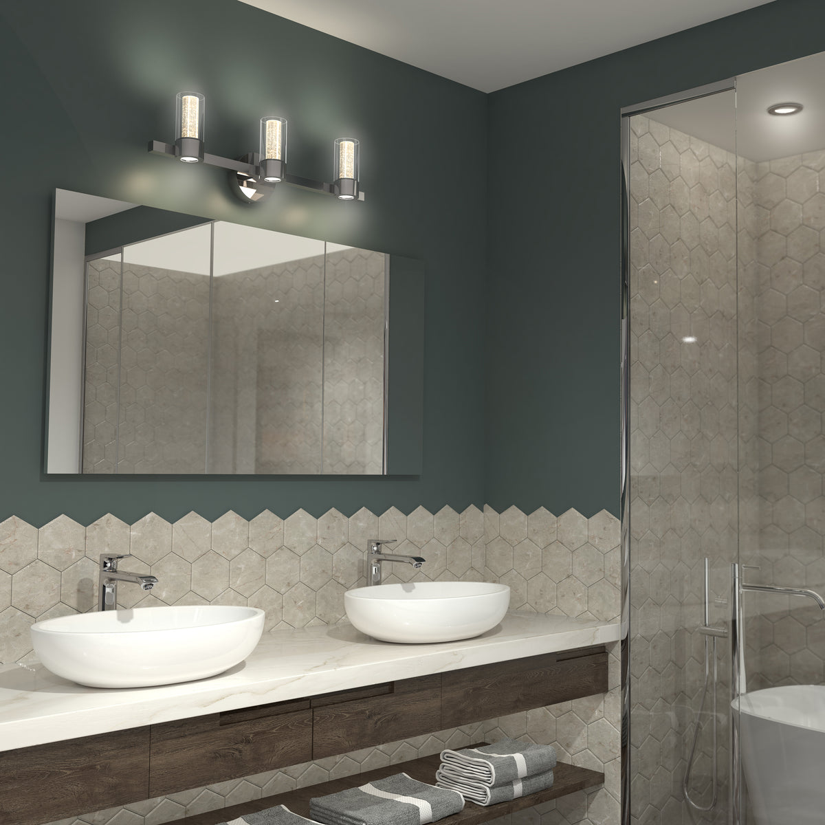 Modern bathroom with a double sink vanity, round vessel sinks, wall-mounted faucets, hexagon tile backsplash, a large mirror, overhead three-light fixture, and a glass shower enclosure. Folded towels are on the vanity.