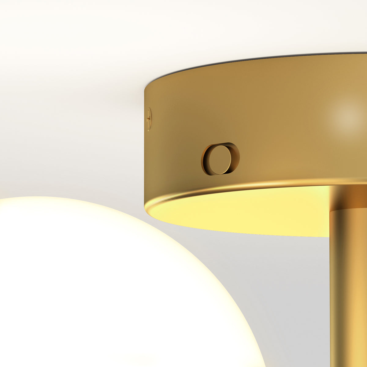 A close-up of a modern lamp with a golden metal shade and a round, glowing white bulb next to it, set against a light background. The design appears minimalistic and elegant.