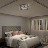 A cozy bedroom with a tufted gray headboard, white bedding, blush pillows, a modern crystal ceiling light, nightstands with lamps, and sheer curtains allowing natural light through the window.
