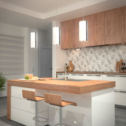 Modern kitchen with a wooden island, two bar stools, Artika Subway Round Mini LED pendant lights, white cabinets, and a hexagon tile backsplash. A plant sits in the corner and kitchen essentials are neatly arranged.