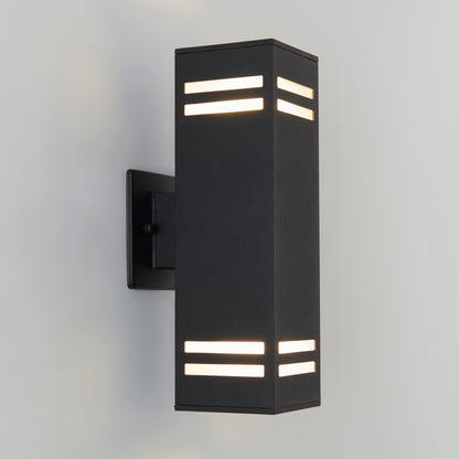 The Artika Strike indoor-outdoor wall light is a modern black rectangular sconce featuring horizontal top and bottom slits, mounted on a light-colored wall and emitting soft white light.