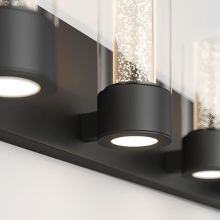 Close-up of Artika Essence 27-in Modern LED Vanity Light, featuring a sleek black base and cylindrical glass shade.