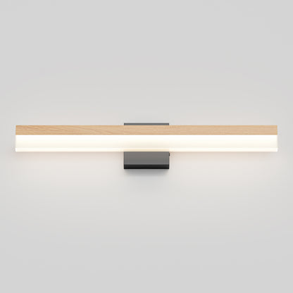 The Artika Neil modern LED bathroom vanity light features a minimalist design with a rectangular wooden accent atop a long, horizontal frosted diffuser, all mounted on a small black square base against a white wall.