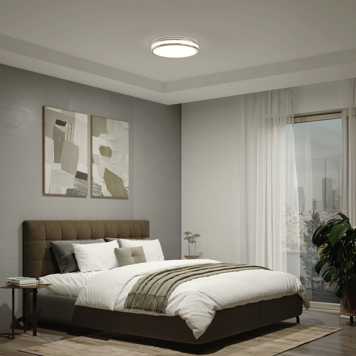 A modern bedroom featuring a brown upholstered bed, white bedding, two abstract art pieces, sheer curtains, a potted plant, city views through large windows, and an Artika Hemisphere 15 in. LED flush mount light with 5 CCT adjustable brightness.