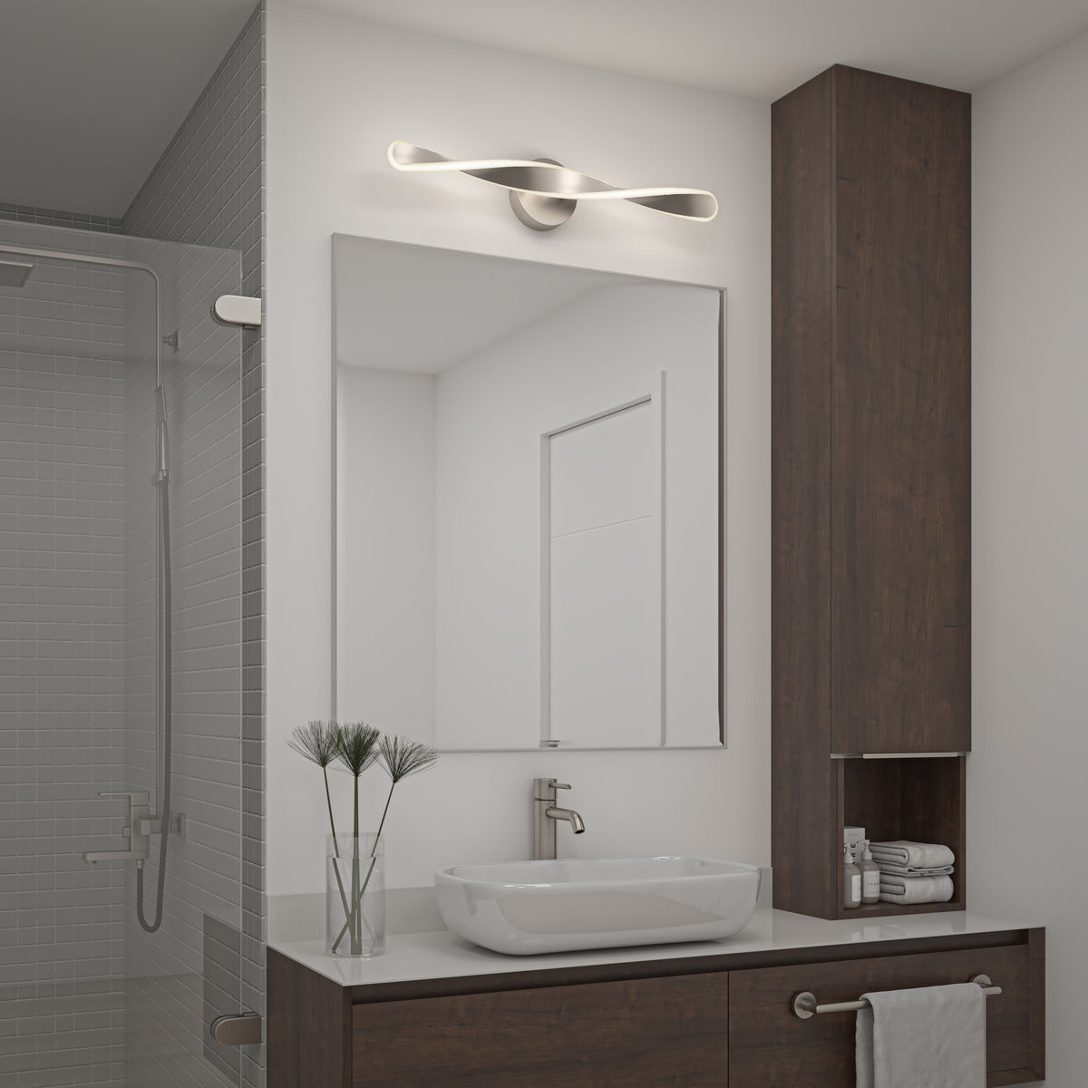 A modern bathroom with a rectangular mirror above a sink, a sleek looped light fixture above the mirror, a wooden cabinet, glass shower, and neatly arranged towels and plants on the counter.