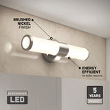 A modern bathroom wall light with a brushed nickel finish and two tubular LED lights. Text highlights features: energy efficient, no bulbs required, integrated LED, and a 5-year warranty. The light is mounted above a mirror.