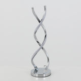 A modern table lamp with two chrome spiral arms twisting upward on a round base, set against a plain white background.