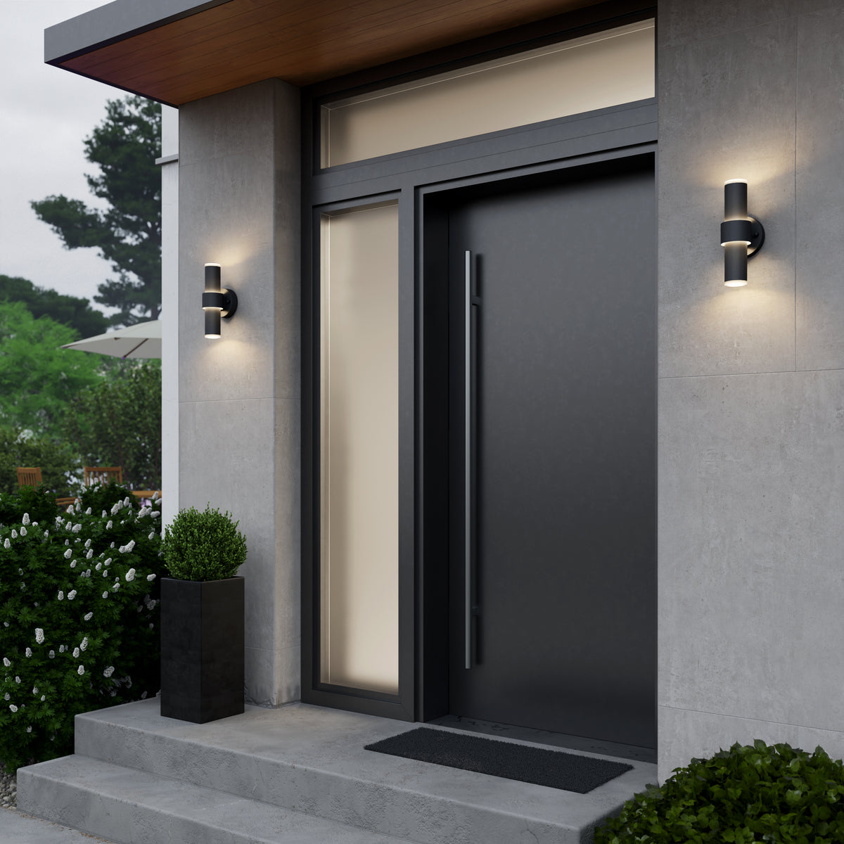 Modern front door with a sleek black finish, large vertical handle, side and transom windows, two wall-mounted lights, a square planter with greenery, and concrete steps leading up to the entrance.