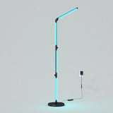 A modern floor lamp with a slim black stand and arm, featuring vertical and angled blue LED light strips, plugged into a wall outlet on a plain light gray background.
