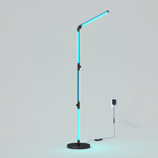 The Artika Fitch smart foldable RGB LED gaming floor lamp features a slim black stand, glowing blue LED segments, and a simple round base, plugged into a wall socket and set against a plain light background.