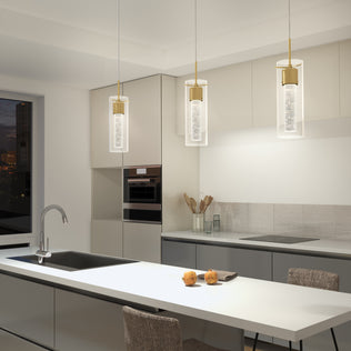 Modern kitchen with neutral tones, a large island with a sink, two apples on the counter, built-in appliances, and three Artika Essence LED pendant lights hanging above the island.
