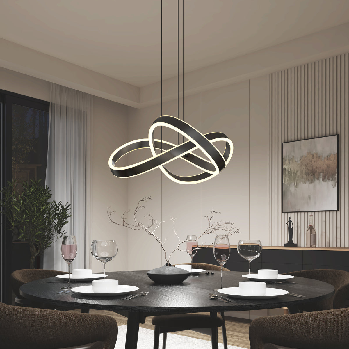 A modern dining room with a round black table set for four, featuring white plates, wine glasses, and a minimalist centerpiece. An abstract, intertwined LED chandelier hangs above. Contemporary decor and wall art complete the scene.