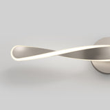 A modern ceiling light fixture with a metallic finish and an infinity loop design, emitting a soft white glow, set against a plain gray background.