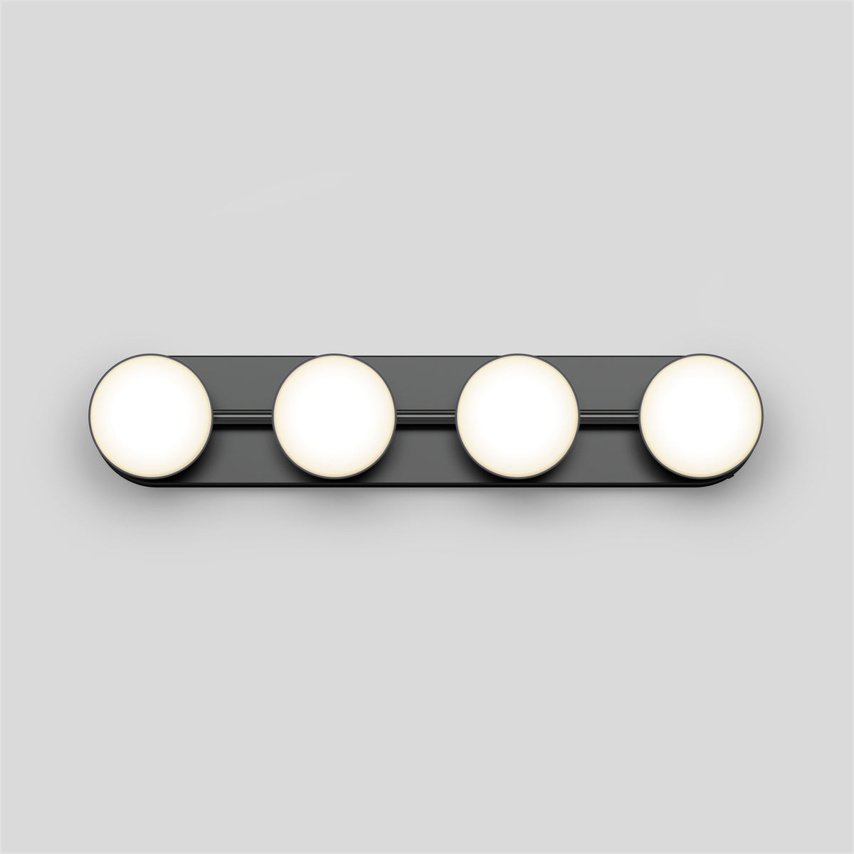 A horizontal black light fixture with four evenly spaced round white bulbs mounted on a light gray wall.