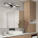 Modern bathroom with a rectangular mirror above a white sink, matte black faucet, light wood cabinets, a decorative branch in a vase, soap dispenser, and a curved LED light fixture mounted above the mirror.