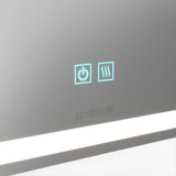 A close-up of a mirror featuring two illuminated touch icons: a power symbol and a heated mirror symbol. The brand name artika is visible below, and a horizontal LED light runs along the bottom edge.