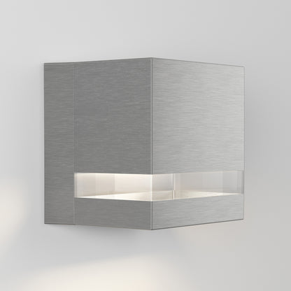 The Valor Square LED indoor/outdoor wall light by Artika-CAN-dev features a modern cube design with a brushed metal finish and horizontal frosted band emitting soft white light, shown mounted on a plain white wall.