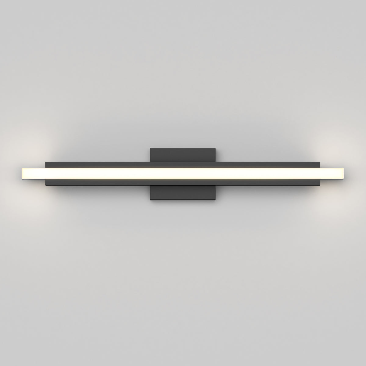 A modern wall-mounted LED light fixture with a long horizontal bar emitting white light, attached to a central rectangular black base on a plain light gray wall.