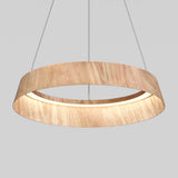 A modern circular pendant light fixture with a wood finish, suspended by thin wires against a plain gray background. The inner edge of the ring emits a soft, even light.