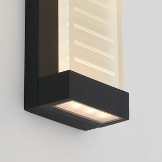 The Artika Percy LED indoor-outdoor wall light features a modern rectangular design with a black frame and frosted white panel, mounted on a light-colored wall, emitting soft downlighting from the bottom.