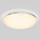 A round, flush-mounted ceiling light fixture with a textured, glowing white surface and a metallic rim, emitting soft, diffused light against a light gray background.