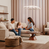 A man, woman, and young girl sit together on a beige couch in a modern living room, talking and smiling. The room has neutral tones, a round wooden coffee table, and a woven basket on the floor.