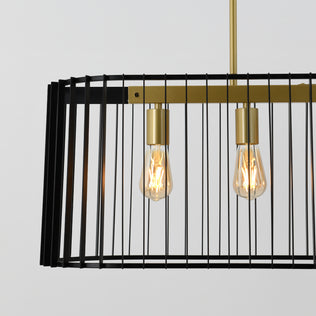 Close-up of the Artika Gatsby LED pendant light featuring two exposed bulbs in a rectangular black metal cage with gold accents, suspended from a gold rod against a light background.