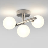 A modern ceiling light fixture with a brushed metal base and three frosted glass globes arranged in a triangular pattern, each orb emitting a soft white glow.