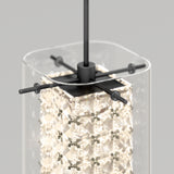 A close-up of a modern pendant light featuring a clear rectangular glass shade, a square metal frame, and an illuminated inner crystal structure with intricate geometric patterns.