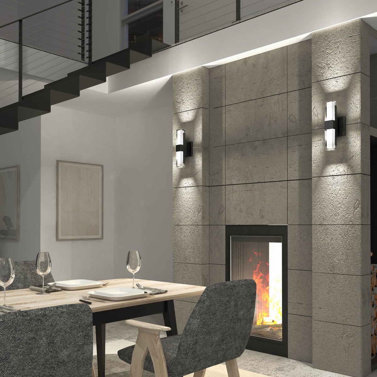 Modern dining room with a wooden table for four, gray upholstered chairs, and a concrete fireplace. Artika’s Gemini indoor-outdoor LED wall lights illuminate the space beneath an open staircase adorned with artwork.