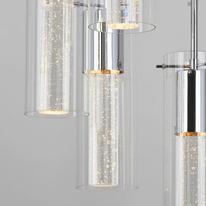 Close-up of the Artika Bubble Swirl 5-light pendant, featuring cylindrical glass shades with bubbles, emitting a warm glow from a chrome fixture against a plain gray background.
