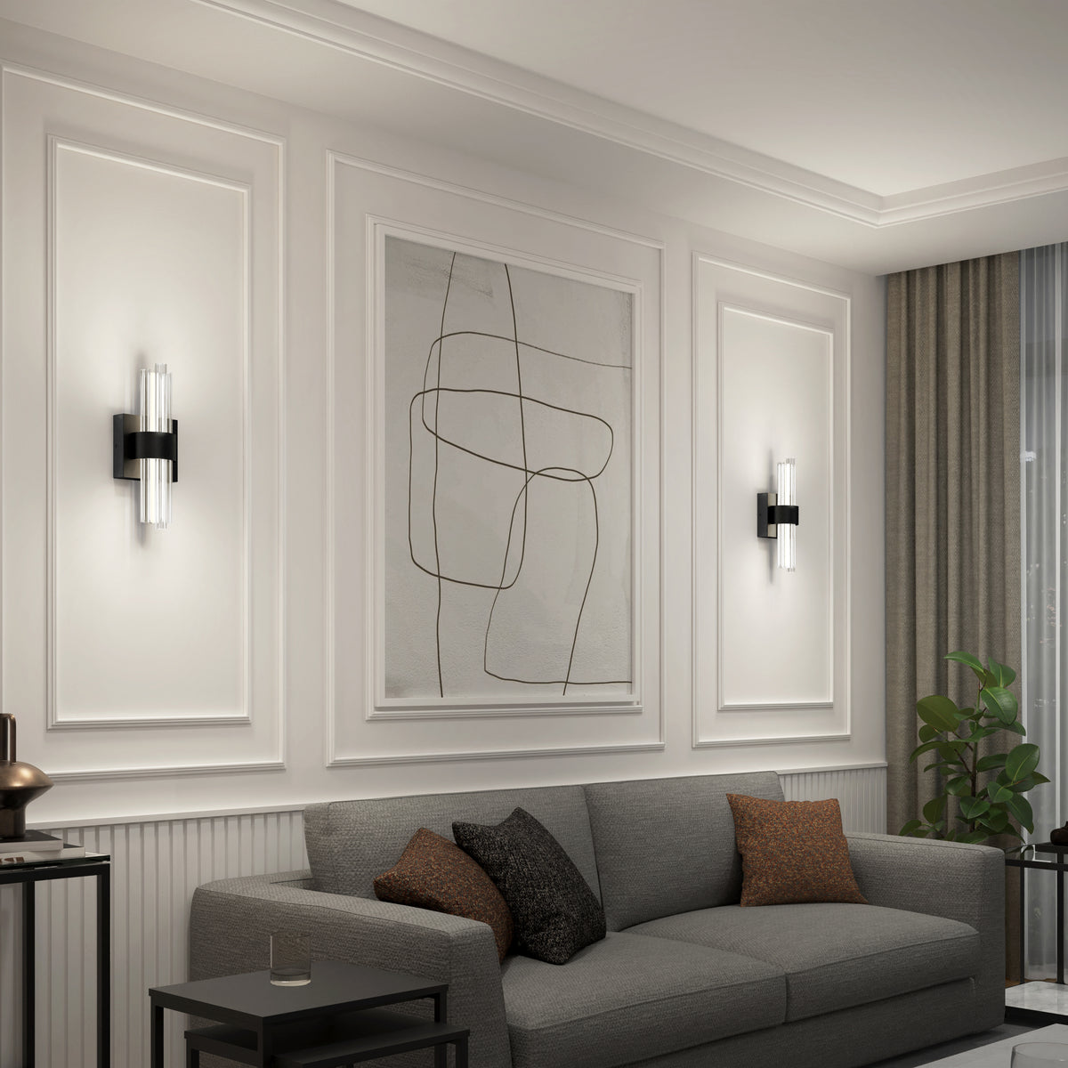 A modern living room with a gray sofa, brown and gray cushions, abstract wall art, two wall-mounted light fixtures, a side table, and a potted plant near large curtains. The walls have elegant panel detailing.