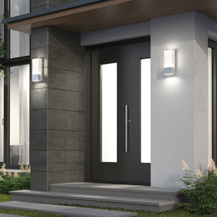 Modern front door with large vertical glass panels, gray siding, white walls, and small green plants along the steps. Two Artika Dixon indoor-outdoor LED wall lights add stylish contemporary lighting to this elegant entrance.