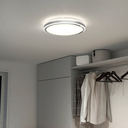 The Artika Altitude 15 in. LED modern flush mount light with 5 CCT settings illuminates a minimalist room featuring gray cabinets, a closet with hanging clothes, and storage boxes on the upper shelf.