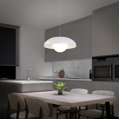 A modern kitchen with grey cabinets, marble backsplash, built-in appliances, and a wooden dining table with four chairs. The Artika Boden LED modern mid-century pendant light 3 CCT hangs above the table, illuminating a potted plant.