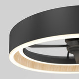 Close-up of a modern ceiling fan with a circular black and wood accent frame, featuring integrated LED lighting around the inner edge, set against a plain light gray background.